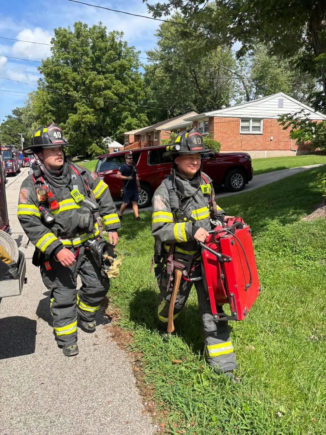 Florissant Valley firefighters walking with tools at a fire scene