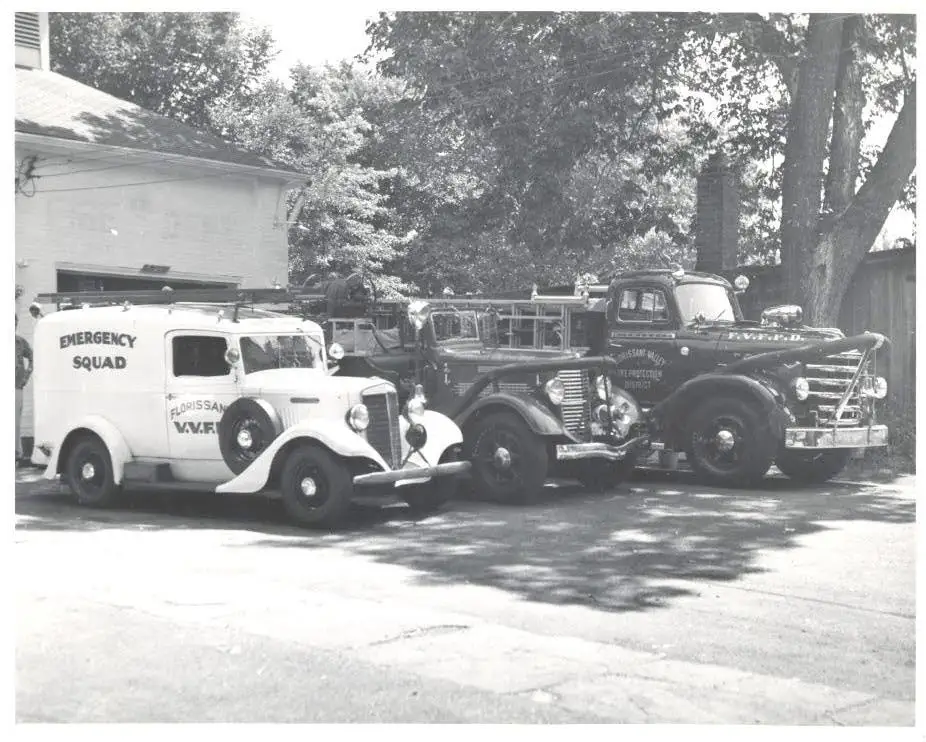 Three of the District's early vehicles — an emergency squad truck and two vintage fire engines — parked outside the station