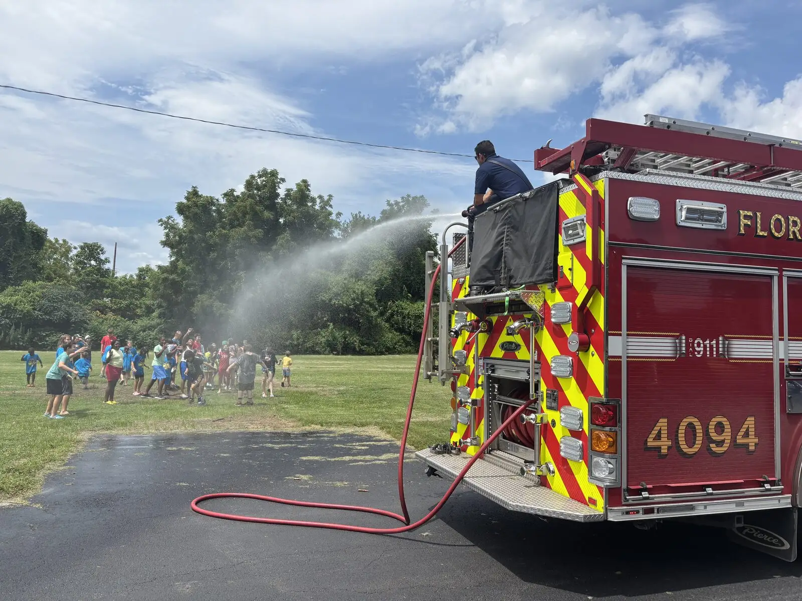 Engine 4094 sprays an arc of water over kids at a summer camp