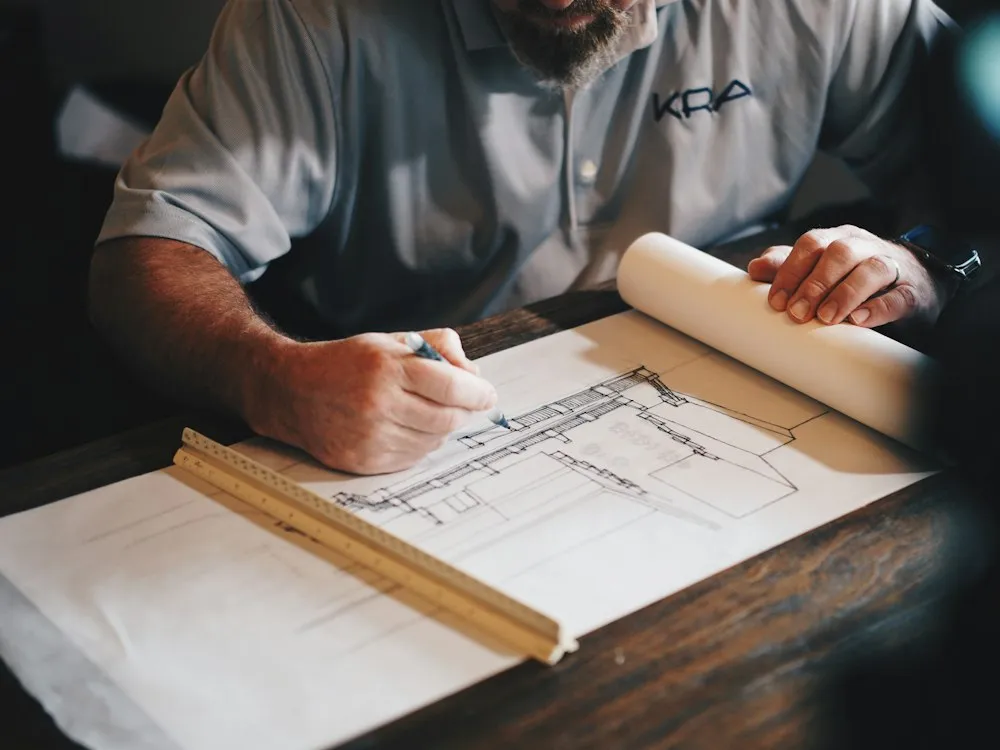 Construction plans being drafted with a pencil and ruler during plan review