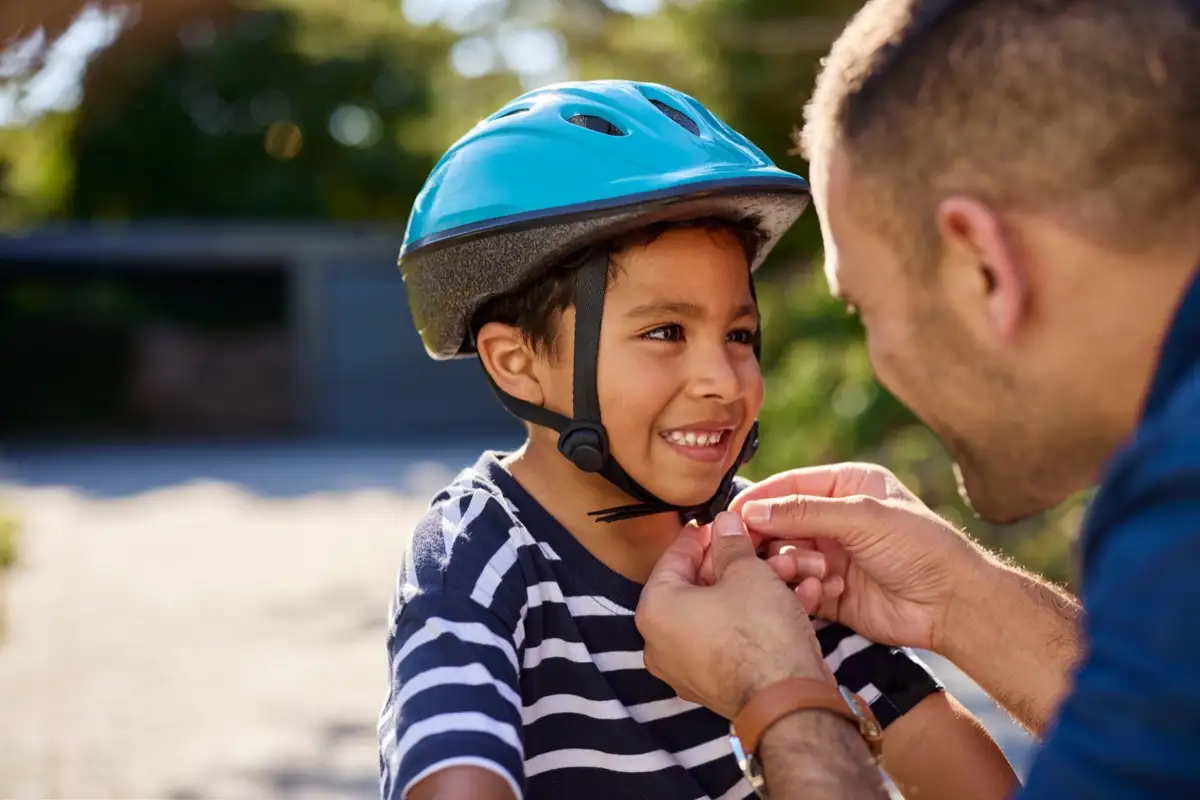 A child having a bicycle helmet fitted and adjusted