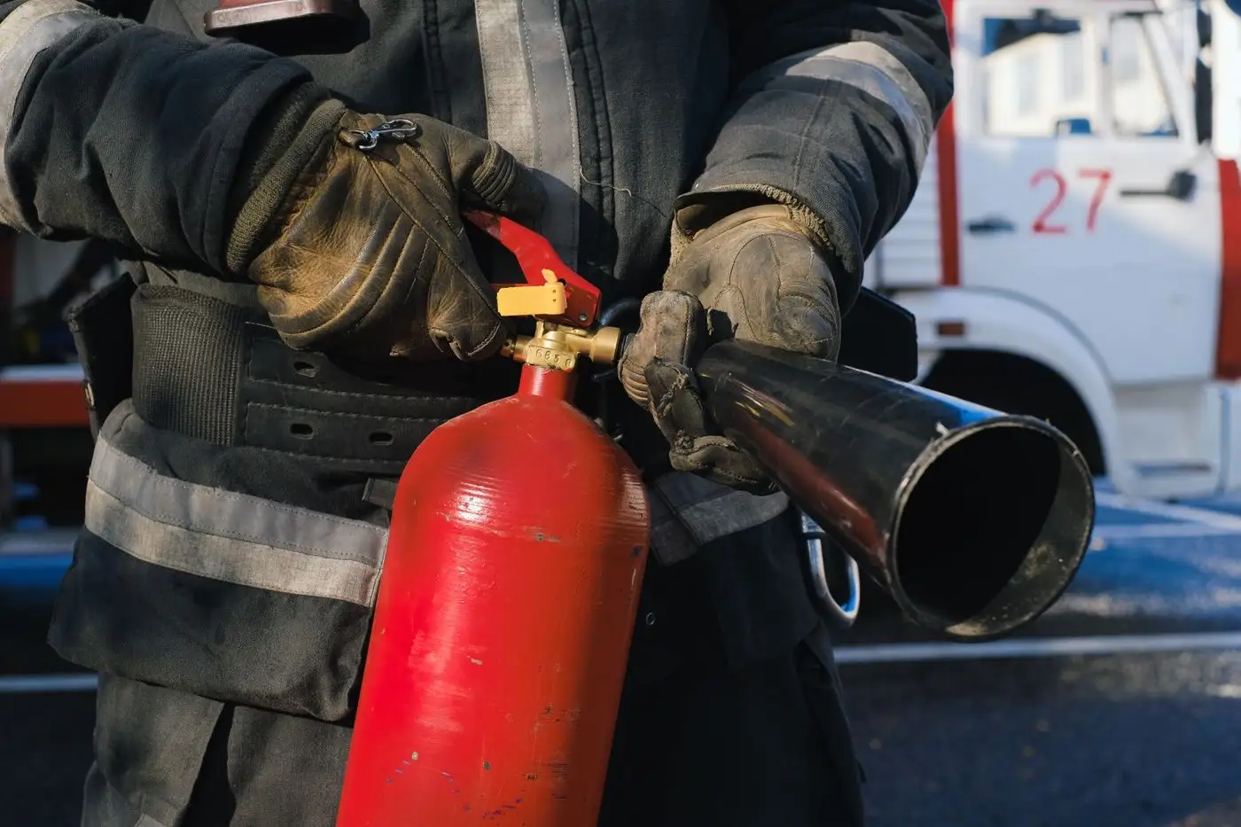 A firefighter in turnout gear holding a fire extinguisher, ready for hands-on fire-suppression training