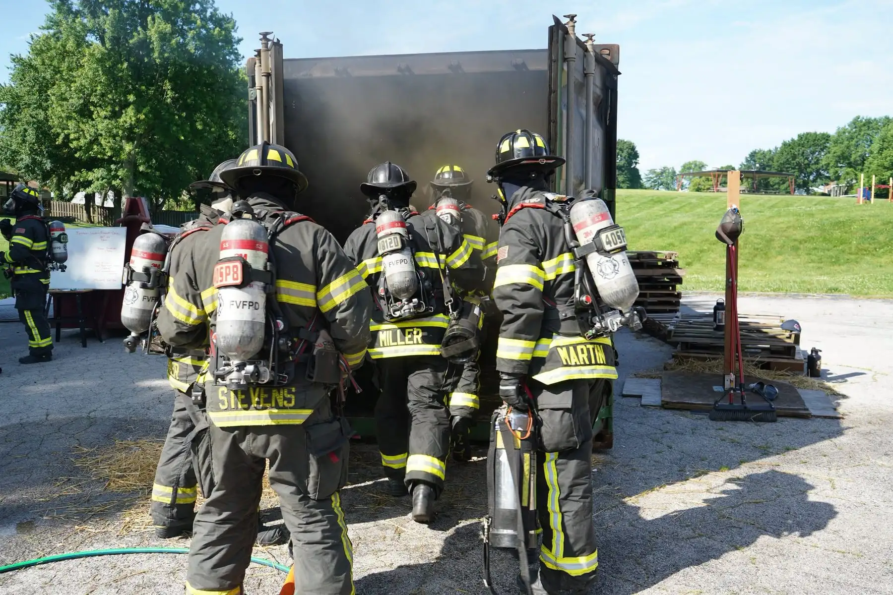 A crew in full turnout gear enters the training burn container during a live-fire drill