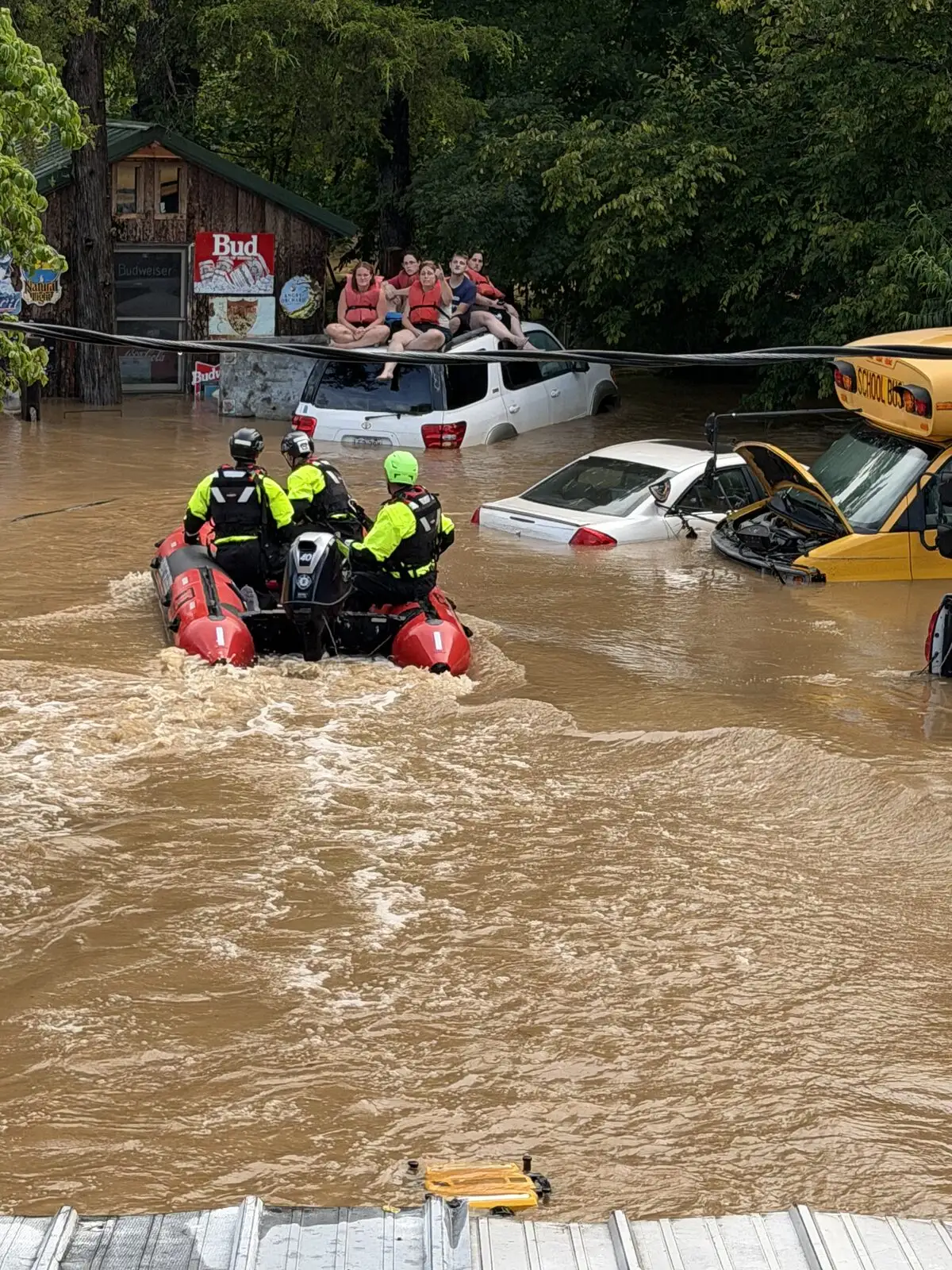 A rescue boat works through floodwater past submerged vehicles